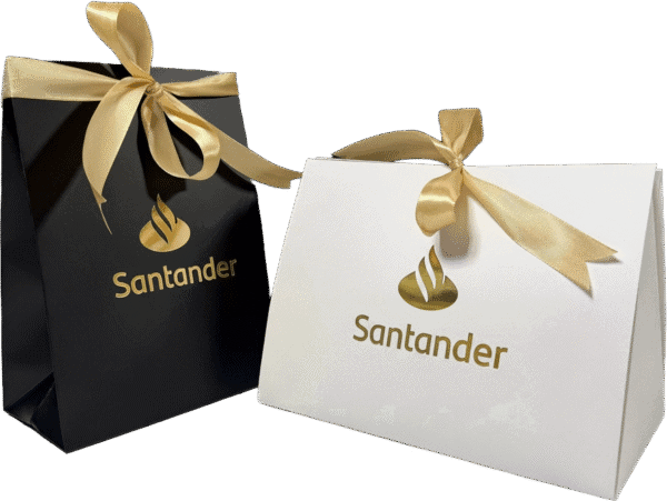 Luksusowe opakowania prezentowe z logo Santander i złotymi wstążkami.